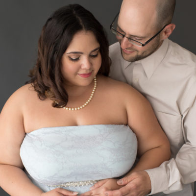 Maternity Indoor Photos of Pregnant woman in Blue Lace gown and Pearls with husband gazing at her in Alachua Florida