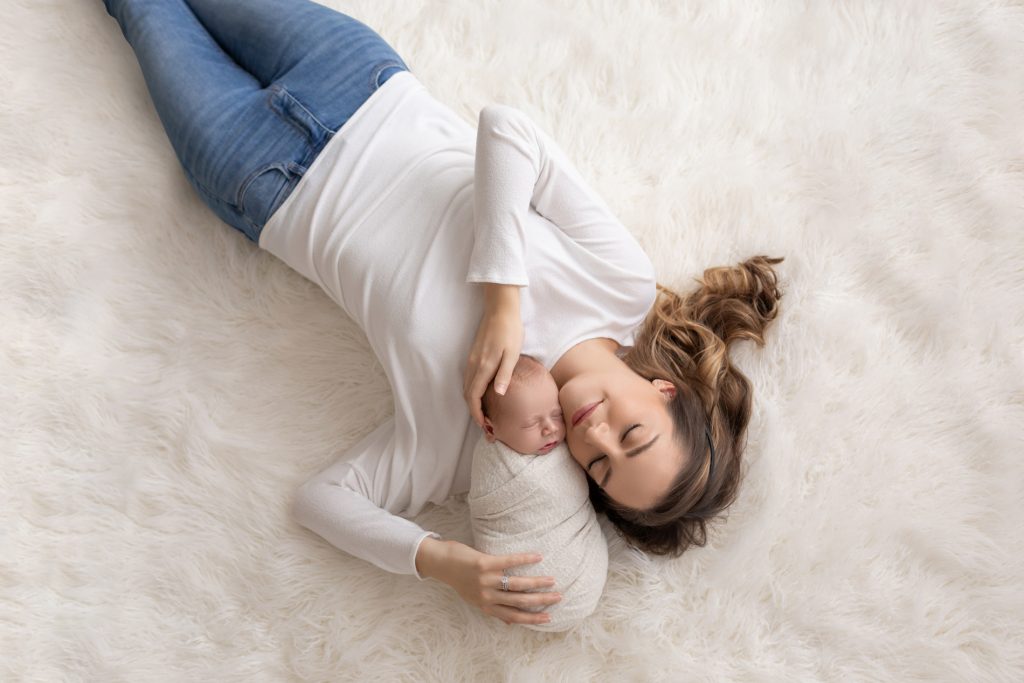 Mom and newborn baby boy on fur rug